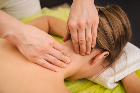 Classical neck and shoulder massage. Beautiful woman enjoying a treatment in a spa center. Body and health care concept.の写真素材