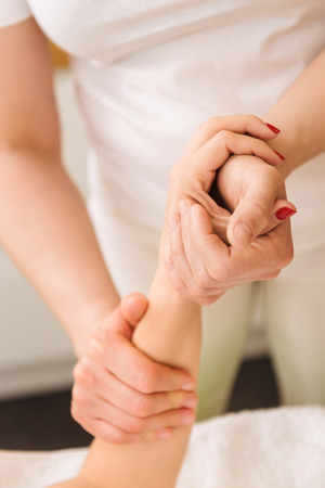 Beautiful young woman receiving hands and wrist massage in a spa center.の写真素材