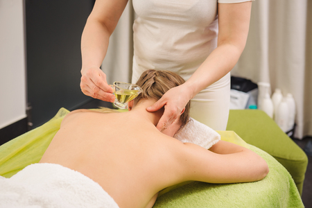 Classical neck and shoulder massage. Beautiful woman enjoying a treatment in a spa center. Body and health care concept.の写真素材