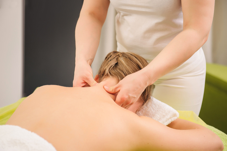 Classical neck and shoulder massage. Beautiful woman enjoying a treatment in a spa center. Body and health care concept.の写真素材