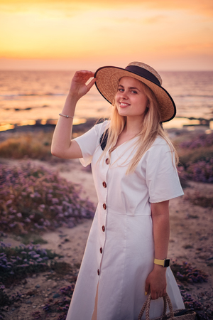 Portrait of beautiful blonde woman in white dress that travel to Cyprus and enjoying summer sea sunset near the lighthouse beach. Freedom conceptの写真素材
