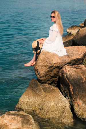 Beautiful blonde woman in white dress travel to Cyprus and relax near coral bay beach. Freedom summer conceptの写真素材