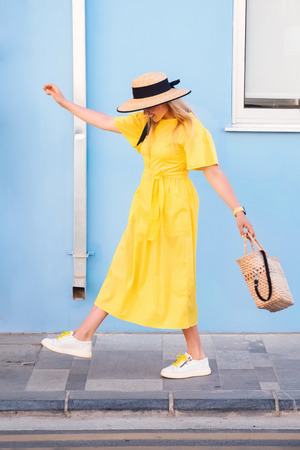 Beautiful blonde woman walking in yellow dress at Paphos old city with colorful door and house. Travel to Cyprus. Fashion summer photoの写真素材