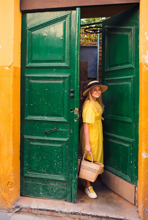 Beautiful blonde woman walking in yellow dress at Paphos old city with colorful door and house. Travel to Cyprusの写真素材