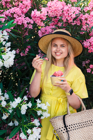 Happy smile blonde woman in yellow dress and hat eat and enjoy ice cream at summer dayの写真素材