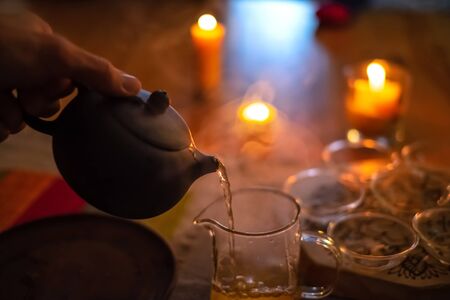Master making chinese tea in traditional ceremony and pouring tea from teapot with vapor on a dark backgroundの写真素材