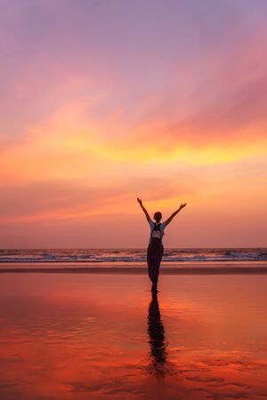 Female silhouette with raised hands feel freedom and enjoying sea view at amazing sunset in GOA beach, India.の写真素材