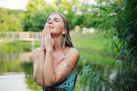 Woman praying portrait at green nature during beautiful sunsetの写真素材