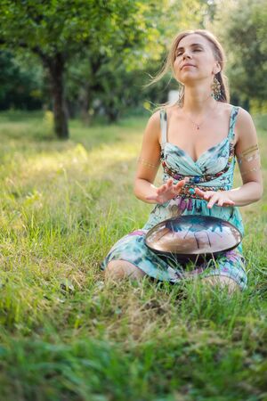 Woman sitting near in the park and playing on happy drumの写真素材