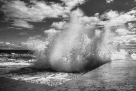Dramatic view of sea waves crashing against the concrete pierの写真素材