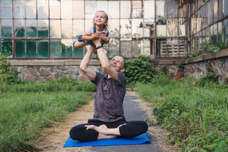 Father and daughter doing yoga together in the parkの写真素材