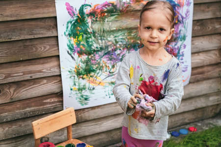 Little girl cleans brush with a rag after paintingの写真素材