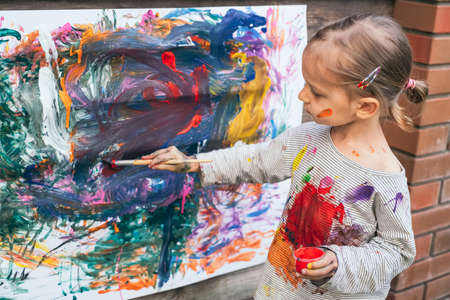 Cute little girl finger painting with various colorsの写真素材