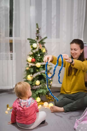 Mom and daughter decorate the Christmas tree at homeの写真素材