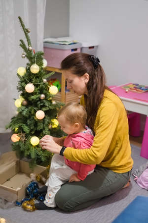 Mom and daughter decorate the Christmas tree at homeの写真素材
