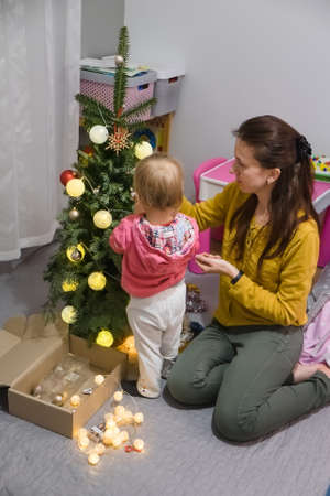 Mom and daughter decorate the Christmas tree at homeの写真素材