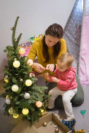 Mom and daughter decorate the Christmas tree at homeの写真素材