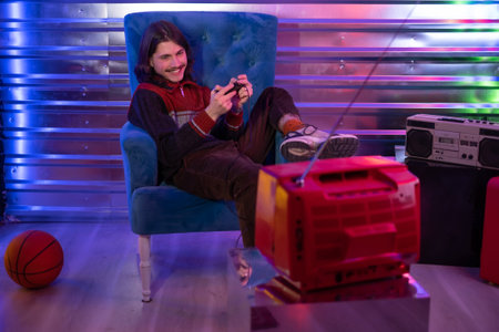 Man playing retro old video TV game in neon style interiorの写真素材