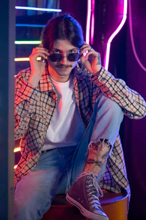 Portrait of millennial man in sunglasses and neon retro styleの写真素材