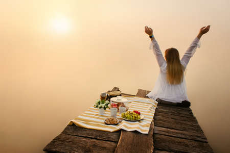 Woman enjoy nature near foggy lake at sunriseの写真素材
