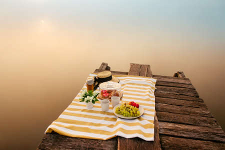 Tasty food for picnic outdoors near foggy lake at sunriseの写真素材