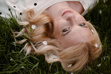 Adult blonde woman portrait from above on the green grassの写真素材