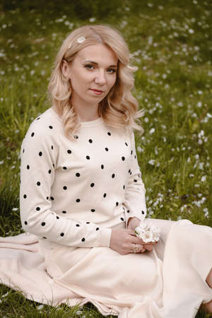 Adult blonde woman sitting on the green grassの写真素材