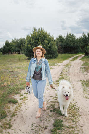 Woman walking with dog on nature out of cityの写真素材