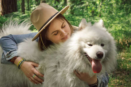Woman hugging her dog samoyed at forestの写真素材