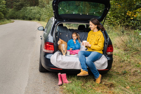 Family road trip with pet, sit in car trunk and eat tasty foodの写真素材