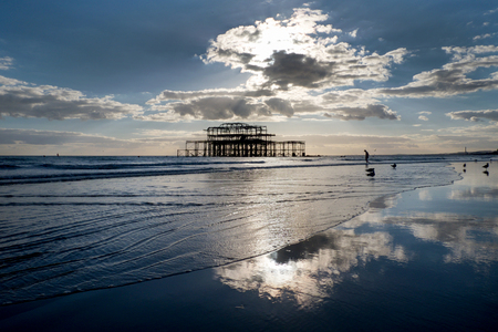 Brighton west Pier at sunset with a solitary man walking into the seaのeditorial素材