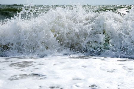 White crashing wave breaking on the seashore with lots of sea sprayの写真素材