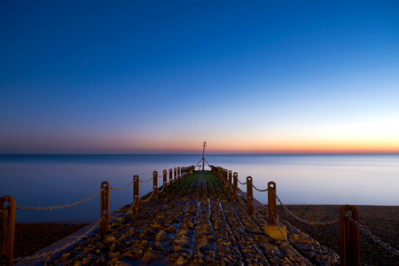 Sunset afterglow of historical jetty on Brighton beach, jutting out over the seaの写真素材