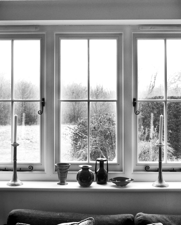 white window frame, with window sill with 2 candles and glass ornaments on white window sill, view through window is garden shrubsの写真素材