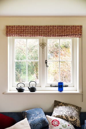 white window frame, with window sill with 2 small metal kettles on, view through window is garden shrubsの写真素材