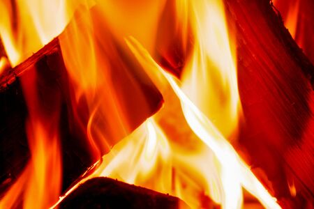 close up of orange and red flames burning on a fire with logsの写真素材