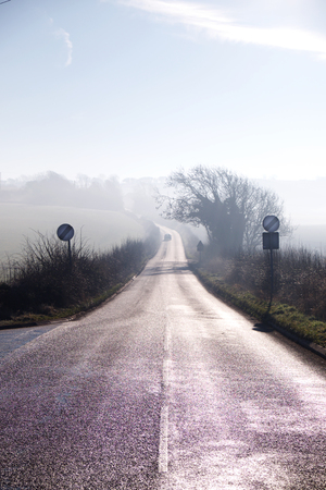 country lane winding into distance on misty morning, road sign, countryside, mist, skyの写真素材