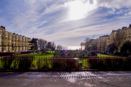 a view of palmeira square, Brighton, regency architecture, town houses, grass park in the centre, sea and skyの写真素材