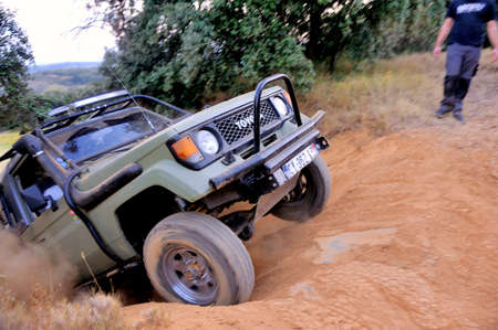 A Toyota Land Cruiser struggling to climb a steep slope to pass