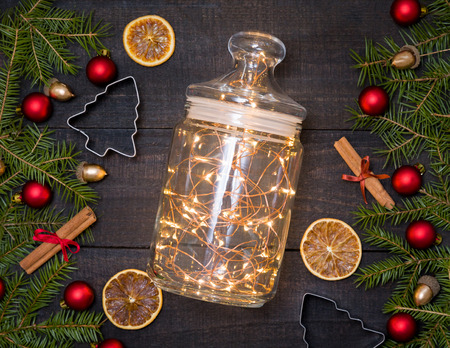 Beautiful glass jar with Christmas lights on dark wood table flatlay with Christmas decorative frame.の写真素材
