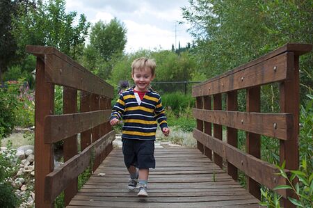 Cute Little Boy Running Across Bridgeの写真素材