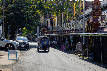 Tuk-tuk on the road next to a temple in Chiang Mai, Thailand.