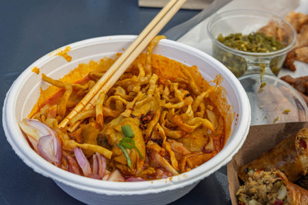 Khao Soi noodles in a white bowl with chopsticks on the table