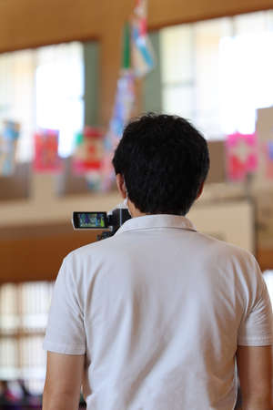 Dad shooting school event with video camera