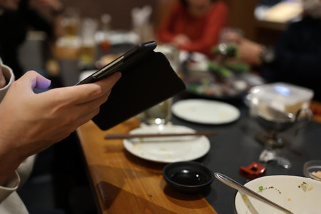 A person operating a smartphone at a drinking partyの写真素材