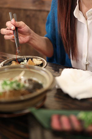 Woman eating with chopsticksの写真素材