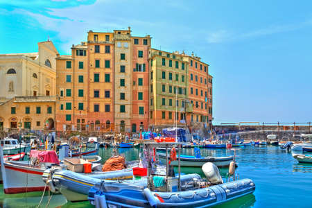 boats in the harbour of the seaport Camogli at the Italian Riviera with a gorgeous colored house facade and luminous shining blue skyのeditorial素材