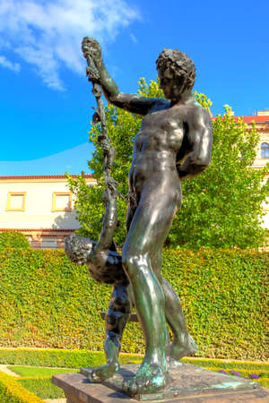 Baroque figures in the green Wallenstein Park in Prague in the Czech Republic with a luminous blue sky and white clouds in the backgroundの写真素材