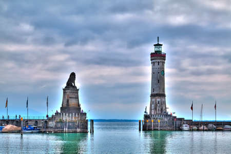 the entrance of the harbour of Lindau at the Lake Constance with the historic lighthouse and the statue of the bavarian lionの写真素材