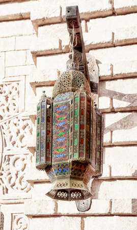 An oriental lamp with artful ornaments is hanging on a building in the medina of the african harbor...
